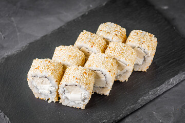 appetizing sushi roll with Philadelphia tofu sesame cheese on a black stone plate