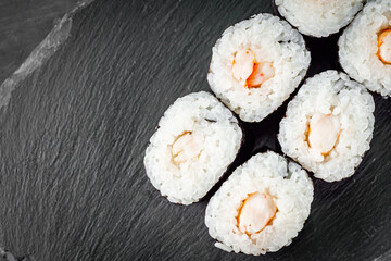 appetizing sushi shrimp maki roll on a black stone plate