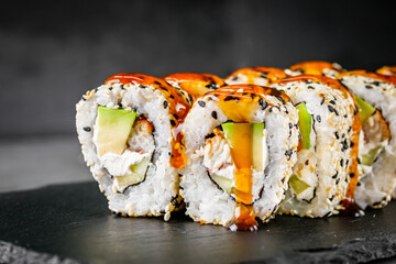 appetizing sushi roll california with eel avocado cucumber and sesame seeds on a black stone plate
