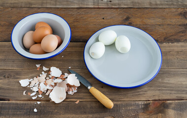 Peeled boiled eggs on a white plate. Bowl with boiled eggs. Wooden background.