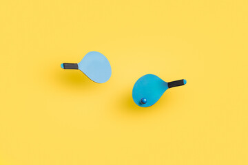 set of blue beach paddles with ball isolated on a yellow background