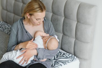 Lactation concept. Young mother breastfeeding her newborn baby at home, close up