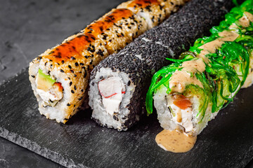 appetizing set of sushi roll on a black stone plate