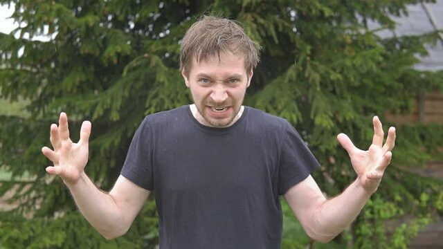 Portrait of angry young man in rain looking furious, aggressive and crazy. Human emotions, facial expressions and abuse, violence concept.