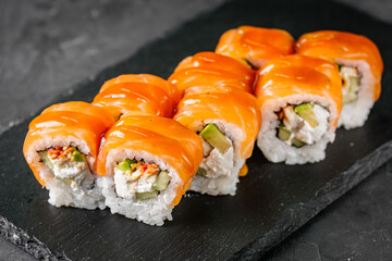 appetizing sushi roll philadelphia with avocado cheese eel cucumber and salmon on a black stone plate