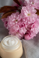 Obraz na płótnie Canvas Anti wrinkle face cosmetic cream or mask with herbal flowers. Skin and body care.Beautiful pink flowers background.