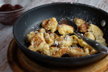 Fresh 'Kaiserschmarrn' in a pan, and plum compote. A traditional sweet meal in Bavaria and Austria.