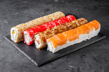 appetizing set of sushi roll on a black stone plate