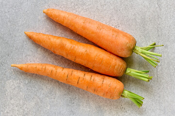Raw ripe carrot fruit on gray background close up