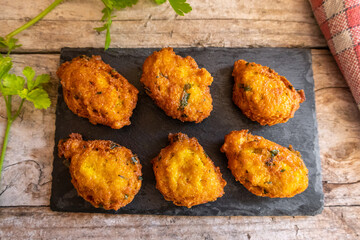 salty fritters with parsley, served on a slate plate and a rustic wood background.