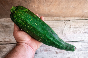 Whole and raw zucchini, on a rustic wooden background. 