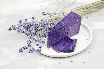 Lavender cheese slices with dry basil and lavender flowers in plate on grey background