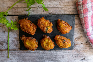 salty fritters with parsley, served on a slate plate and a rustic wood background.