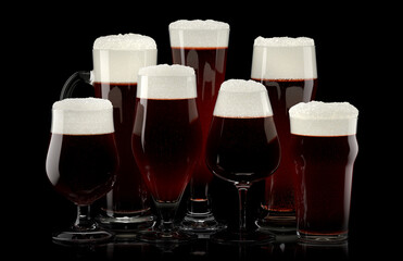 Set of fresh draft beer glasses with bubble froth isolated on black background.