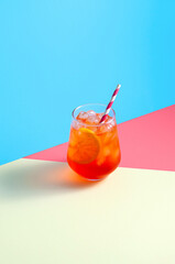 Aperol Spritz Cocktail in glass with ice and orange slice on trendy colorful background. Creative minimal concept