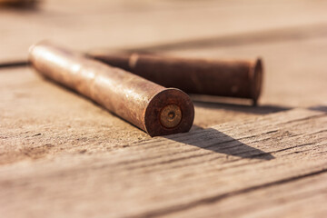 Fototapeta na wymiar Old rusty spent cartridge case from the rifle lies on the wooden surface outdoor