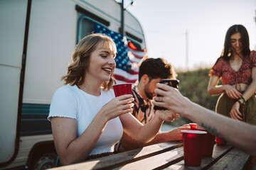 Amigos bebiendo delante de una caravana y sonriendo por el día 4 de julio de estados unidos