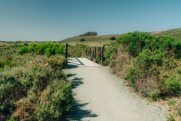 Rural landscape, road through the wilderness area, and wooden boardwalk leading to the beach. Montana de Oro State Park, California