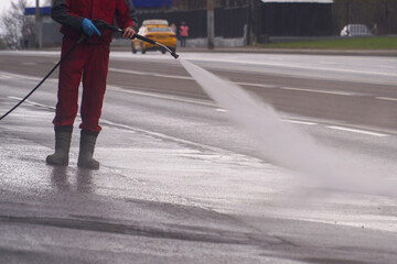  A street cleaner washes the pavement with a high-pressure apparatus.