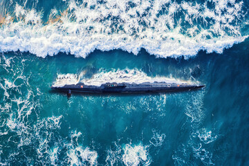 Combat military nuclear diesel electric submarine on background of blue ocean water. Top view...