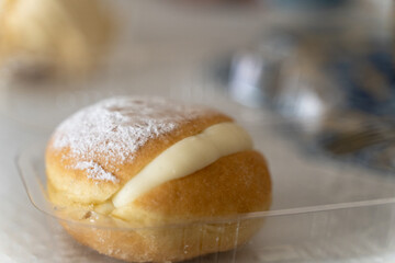 Vanilla custard cream donut with glazed sugar on top. Sweet dessert on plastic container to take away