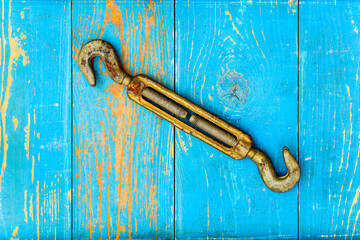Rusty hook on old wooden table covered with blue paint. View from above