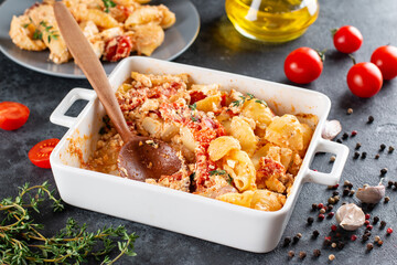 Trending viral Feta bake pasta recipe made of tomatoes, cheese, herbs and garlic in a casserole dish on a dark background