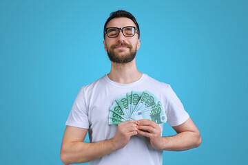 Portrait of confident and proud young bearded man posing with a ward of euro banknotes in hands - obrazy, fototapety, plakaty