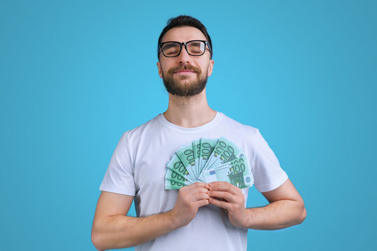 Portrait of confident and proud young bearded man posing with a ward of euro banknotes in hands