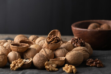 Tasty walnuts with cracked split nutshells, jaw and dragon nutcracker on rustic napkin and wood table