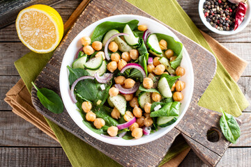 Green vegetable salad with chickpea, spinach, cucumber, red onions, and greens on a table. Top view