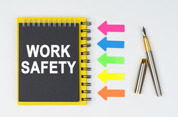 On a white background lies a pen, arrows and a notebook with the inscription - WORK SAFETY