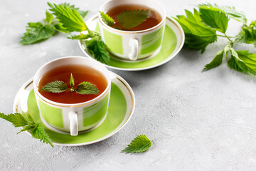 Nettle tea in two cups, fresh stinging nettle herbs. Folk remedy. Copy space