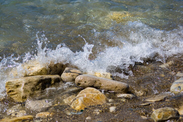 pebble stones on the sea beach, the rolling waves of the sea with foam