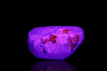 macro mineral stone spinel under ultraviolet light on a black background background