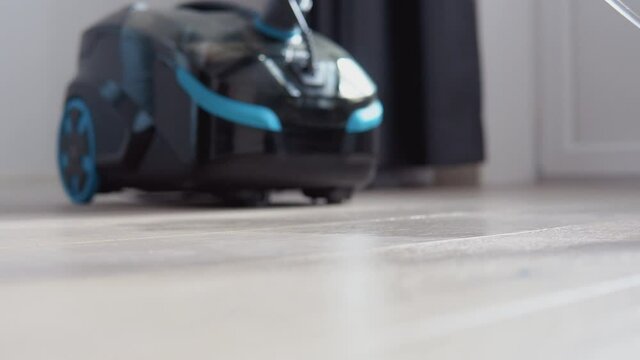 Vacuum cleaning of a light oak floor. The nozzle of the vacuum cleaner goes on a floor