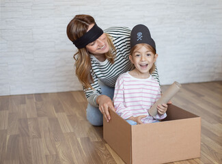 Mother with daughter have fun and playing pirates game, feel playful at home.