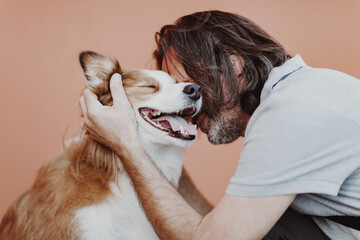 An adult man hugs a ginger dog. Border Collie breed.