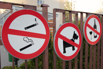 Three prohibition signs - no smoking, no drinking alcohol, no dogs allowed. Signs hanging on the...