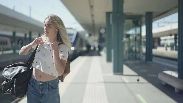Steady shot of an attractive young woman just arrived at the rail station's train track for a holiday, vacation, or Erasmus project in summer.