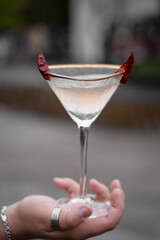 Cocktail in glass with chili on gray background. Devil alcohol drink.