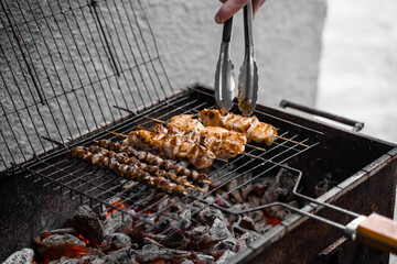 Grilled meat on wooden skewers on metal grill on charcoal. Cooking chicken, hearts.