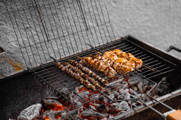 Grilled meat on wooden skewers on metal grill on charcoal. Cooking chicken, hearts.