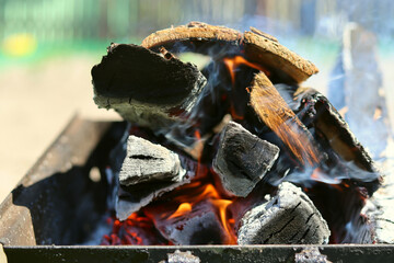 Firewood in the grill, the fire is burning and there is smoke. Open fire, burning wood