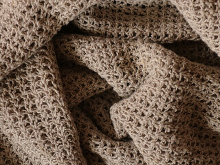 Close up of draped knitted natural linen fabric. Handicraft concept. 