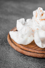 Rice paper chips fried in oil. Rice chips on a wooden board on gray background.