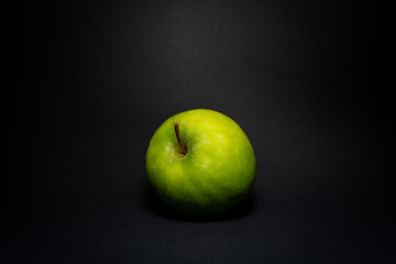 Green tasty apple lies on black background