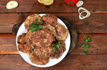 Homemade cutlets with onions, tomatoes and garlic, spicy herbs on a wooden background, delicious natural food, advertising for the menu, cafe restaurant, top view, place for text,