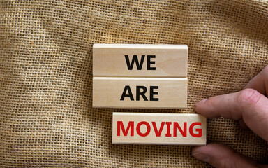We are moving symbol. Wooden blocks with words 'We are moving'. Beautiful canvas background, businessman hand. Business, we are moving concept, copy space.