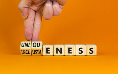 Inclusiveness and uniqueness symbol. Businessman turns wooden cubes, changes words inclusiveness to uniqueness. Beautiful orange background. Business, inclusiveness and uniqueness concept. Copy space.